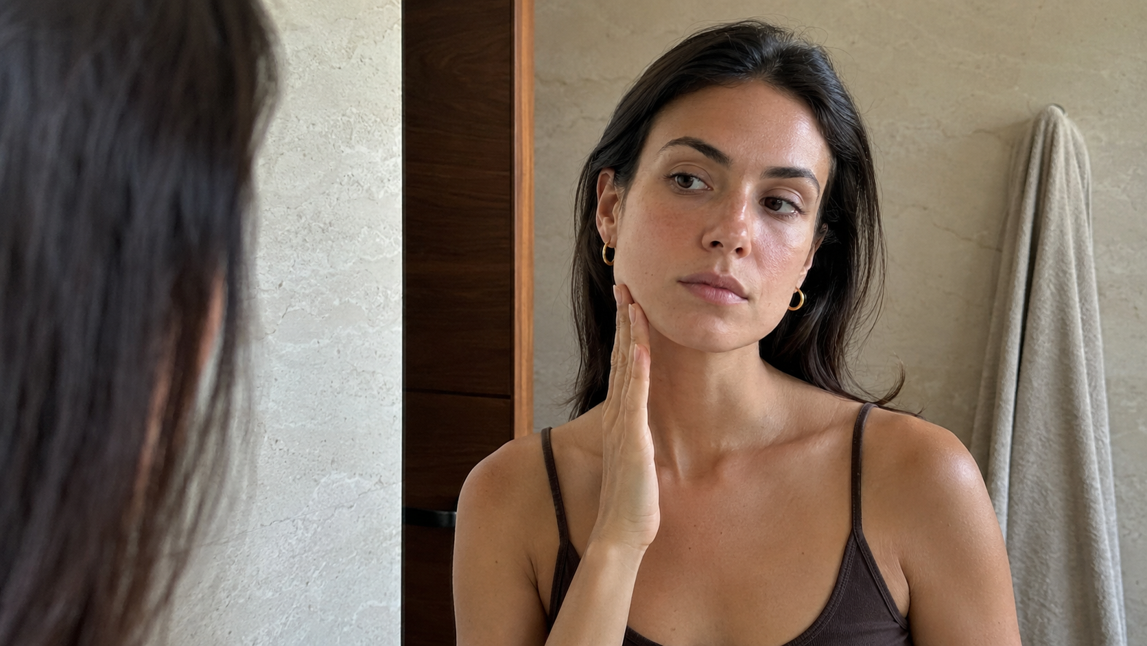 Femme observant son visage dans un miroir pour illustrer une asymétrie du visage et le massage facialiste
